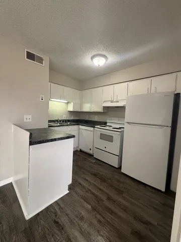 a kitchen with stainless steel appliances a refrigerator a stove a sink and white cabinets