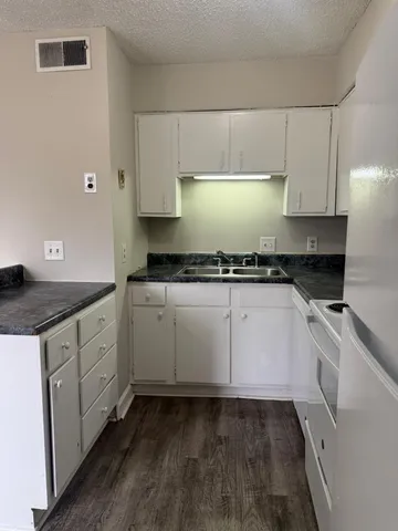 a kitchen with granite countertop white cabinets and white appliances