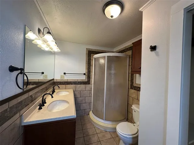 a bathroom with a granite countertop sink a toilet a mirror and shower