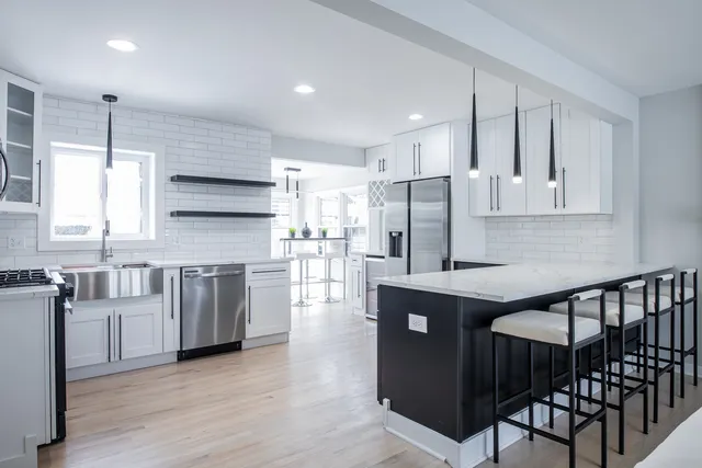 a kitchen with stainless steel appliances granite countertop a refrigerator a stove top oven and a sink