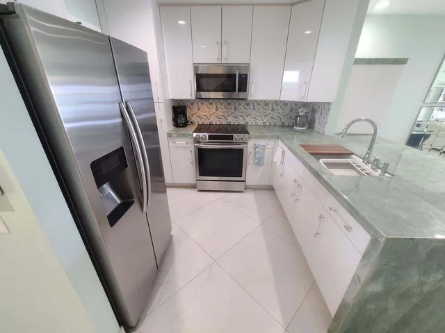 a large kitchen with a sink a microwave and cabinets
