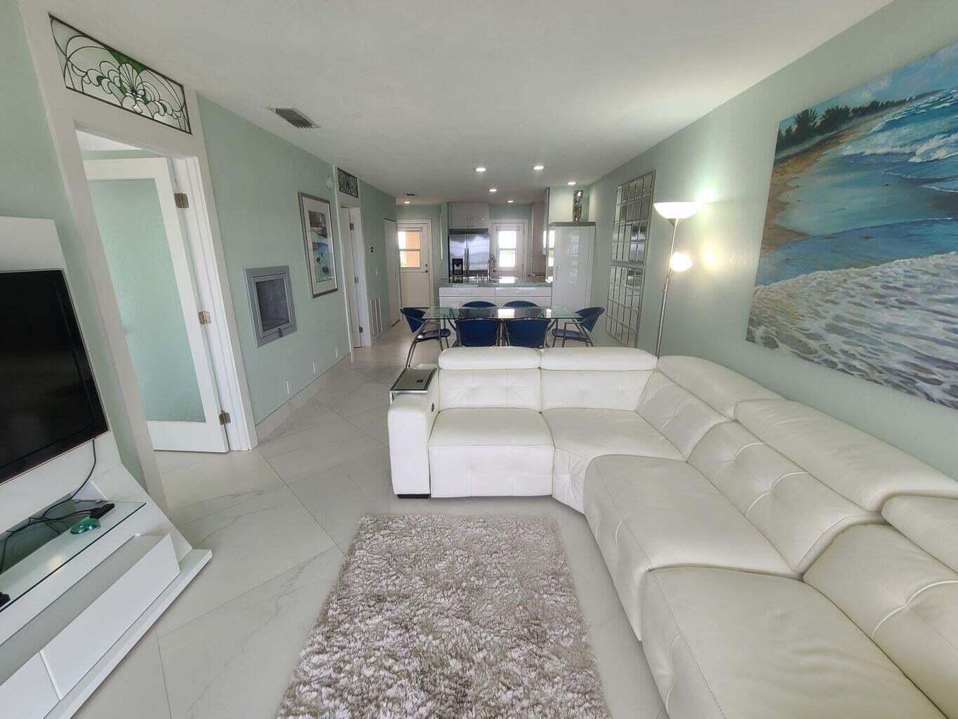 3851 North Ocean Boulevard, Unit 409 Gulf Stream, FL 33483 - Photo 9 of 29 a living room with a couch and a flat screen tv