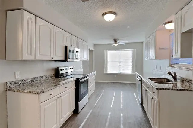 a kitchen with granite countertop a sink stove and cabinets