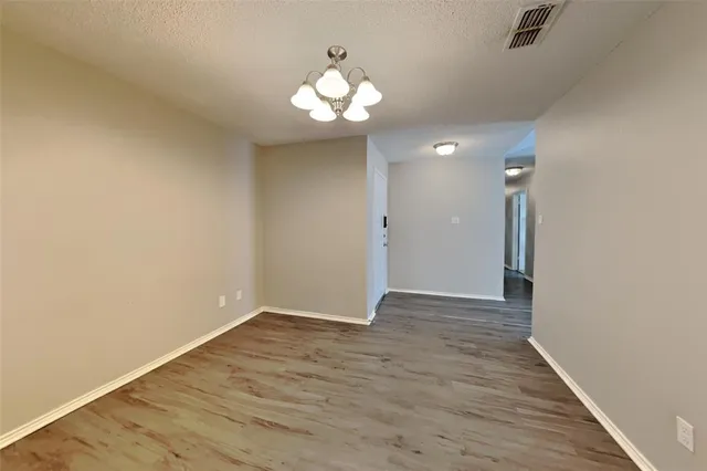 a view of an empty room with wooden floor and a chandelier