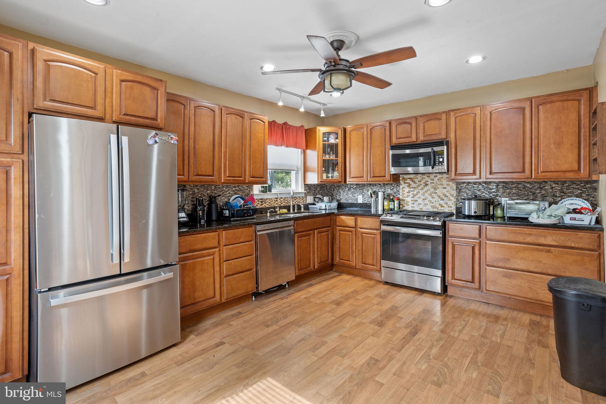 a kitchen with kitchen island granite countertop wooden floors stainless steel appliances and window