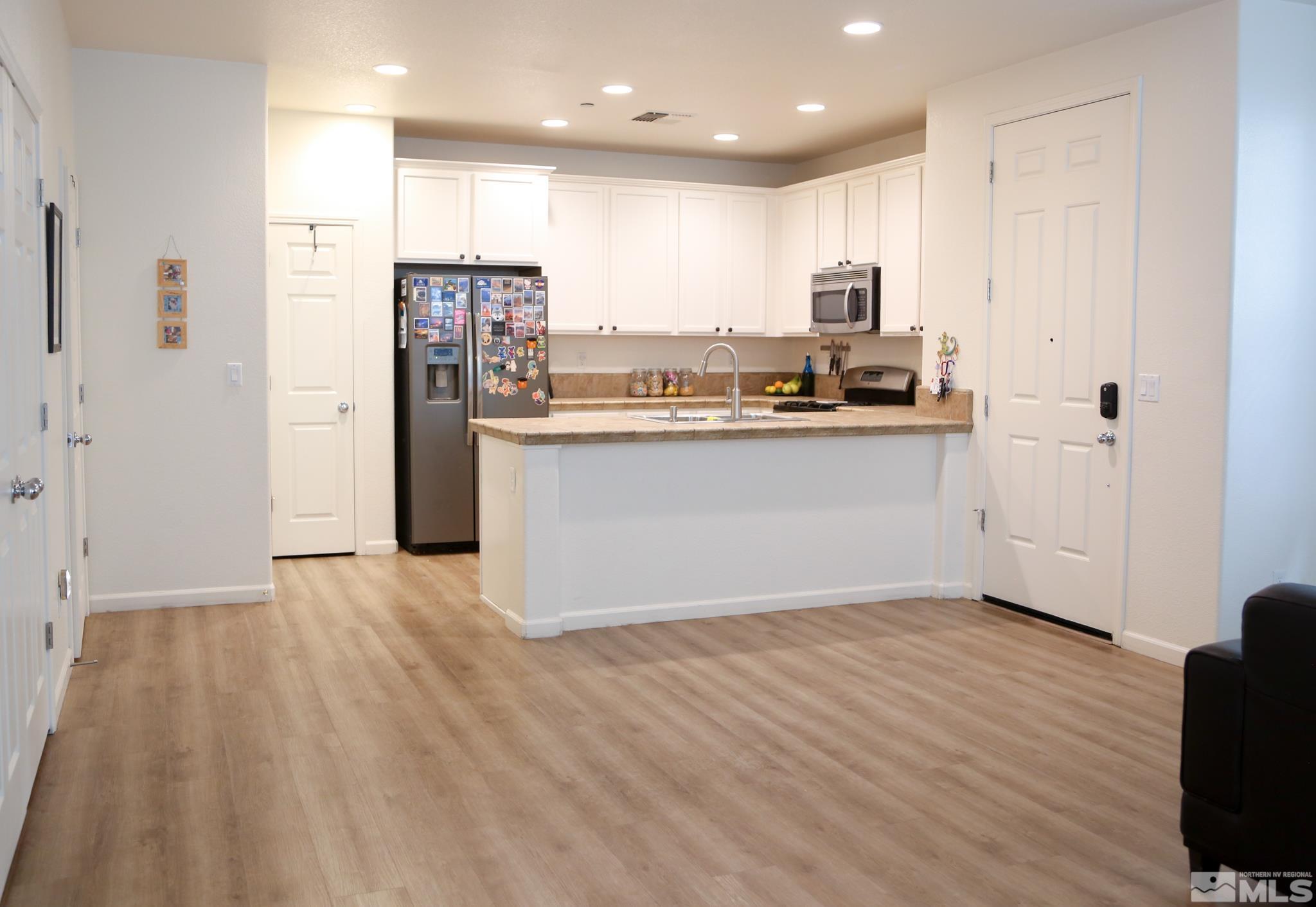 1872 Wind Ranch Road, Unit A Reno, NV 89521 - Photo 6 of 33 a view of kitchen with stainless steel appliances granite countertop a stove top oven a refrigerator and white cabinets with wooden floor