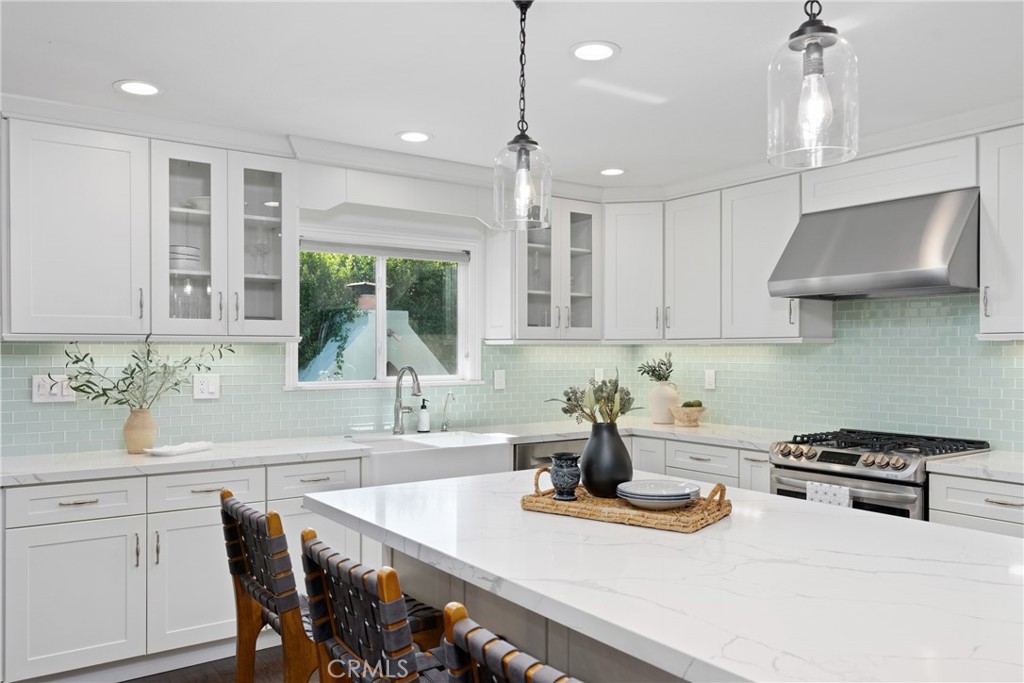 a kitchen with kitchen island granite countertop a sink a stove a dining table and chairs