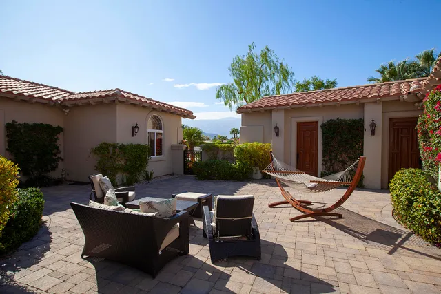 a view of a patio with table and chairs potted plants and floor to ceiling window