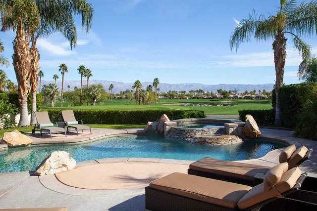 a view of a swimming pool and lounge chairs in the patio