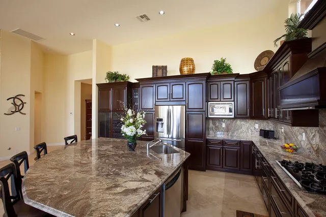 a kitchen with stainless steel appliances granite countertop a sink a stove and a refrigerator