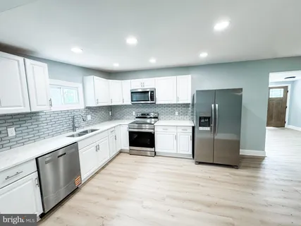 a large kitchen with a large counter top a sink stainless steel appliances and cabinets