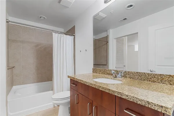 a bathroom with a granite countertop sink a toilet and shower
