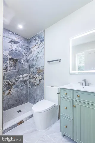 a bathroom with a granite countertop toilet a sink and a mirror