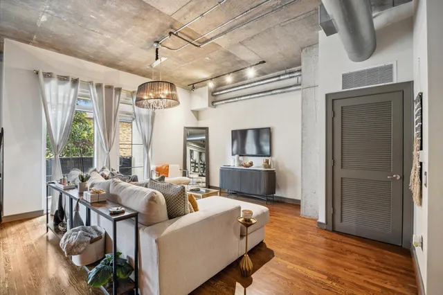 a living room with furniture a large window and wooden floor