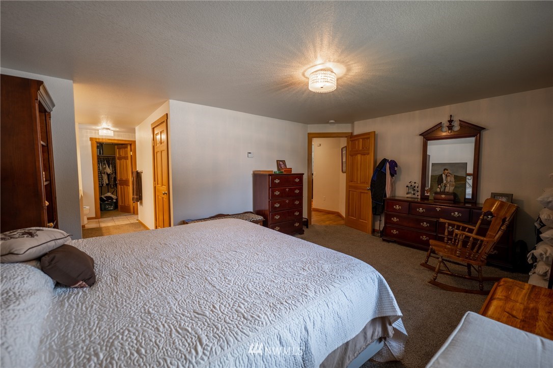 7514 191st Avenue Southwest Rochester, WA 98579 - Photo 18 of 39 a spacious bedroom with a bed and a chandelier