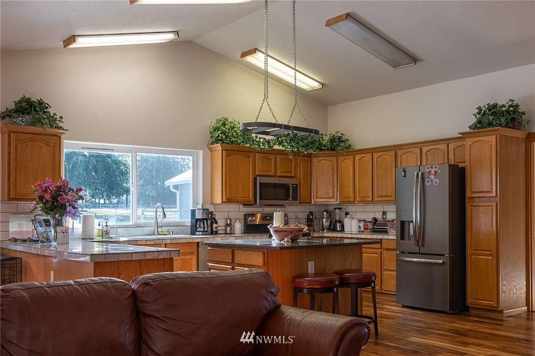 7514 191st Avenue Southwest Rochester, WA 98579 - Photo 28 of 39 a kitchen with stainless steel appliances granite countertop a refrigerator a stove and a dining table with wooden floor