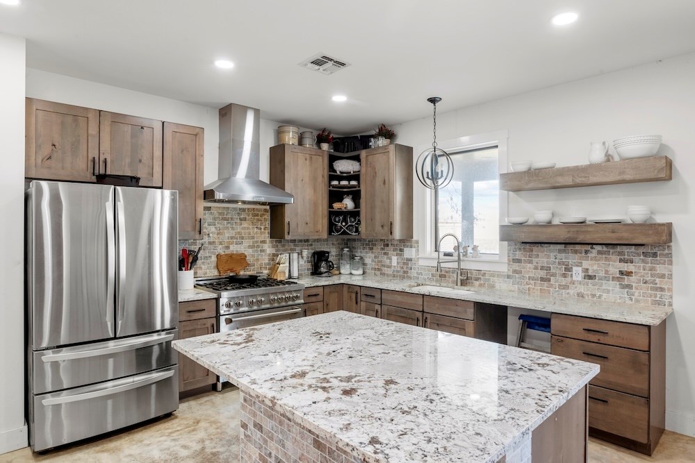 1410 Grapetown Road Fredericksburg, TX 78624 - Photo 23 of 60 a kitchen with kitchen island a counter top and stainless steel appliances