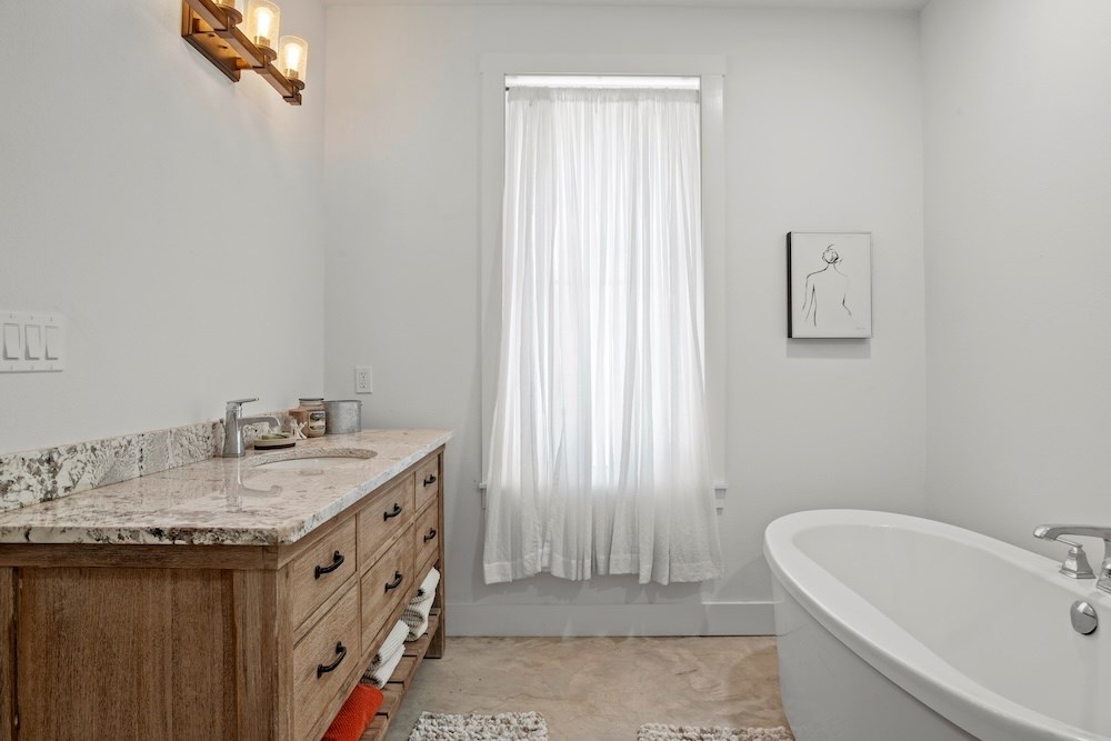 1410 Grapetown Road Fredericksburg, TX 78624 - Photo 30 of 60 a bathroom with a granite countertop sink and a bathtub