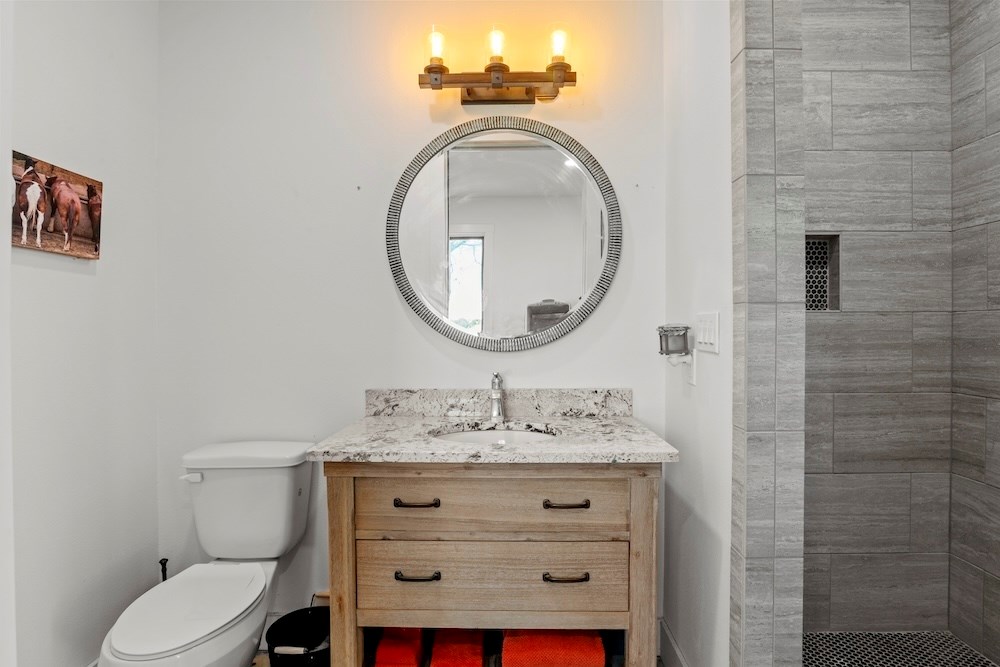 1410 Grapetown Road Fredericksburg, TX 78624 - Photo 33 of 60 a bathroom with a sink a toilet and a mirror