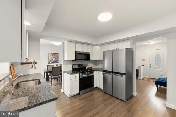 a kitchen with granite countertop a refrigerator stove and sink