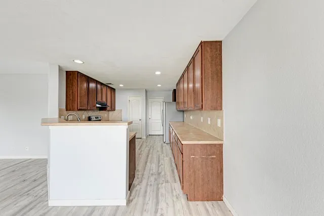 a open kitchen with stainless steel appliances granite countertop a stove top oven a sink dishwasher and a refrigerator with wooden floor