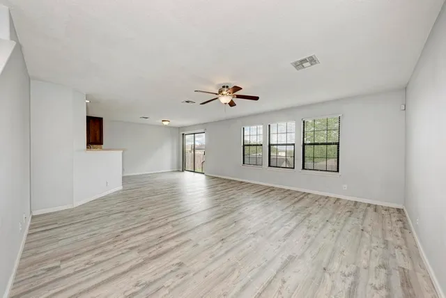 a view of an empty room with a window and wooden floor