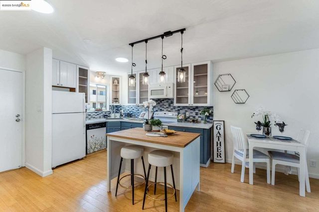 a kitchen with stainless steel appliances kitchen island granite countertop a table chairs stove and white cabinets