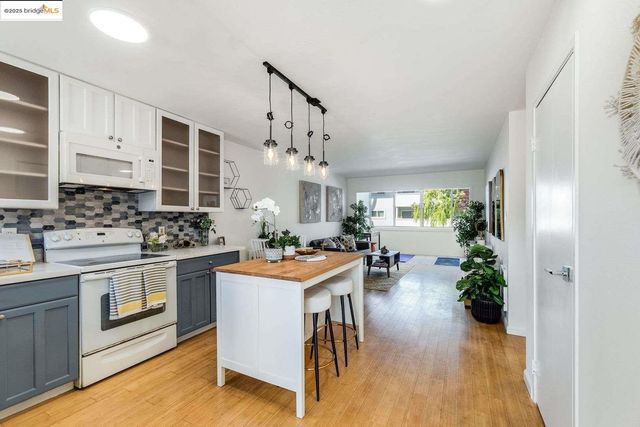 a kitchen with stainless steel appliances granite countertop a stove and a view of living room