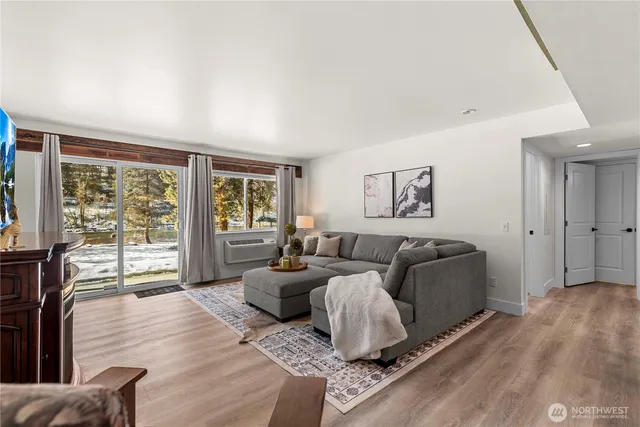 a living room with furniture large window and wooden floor