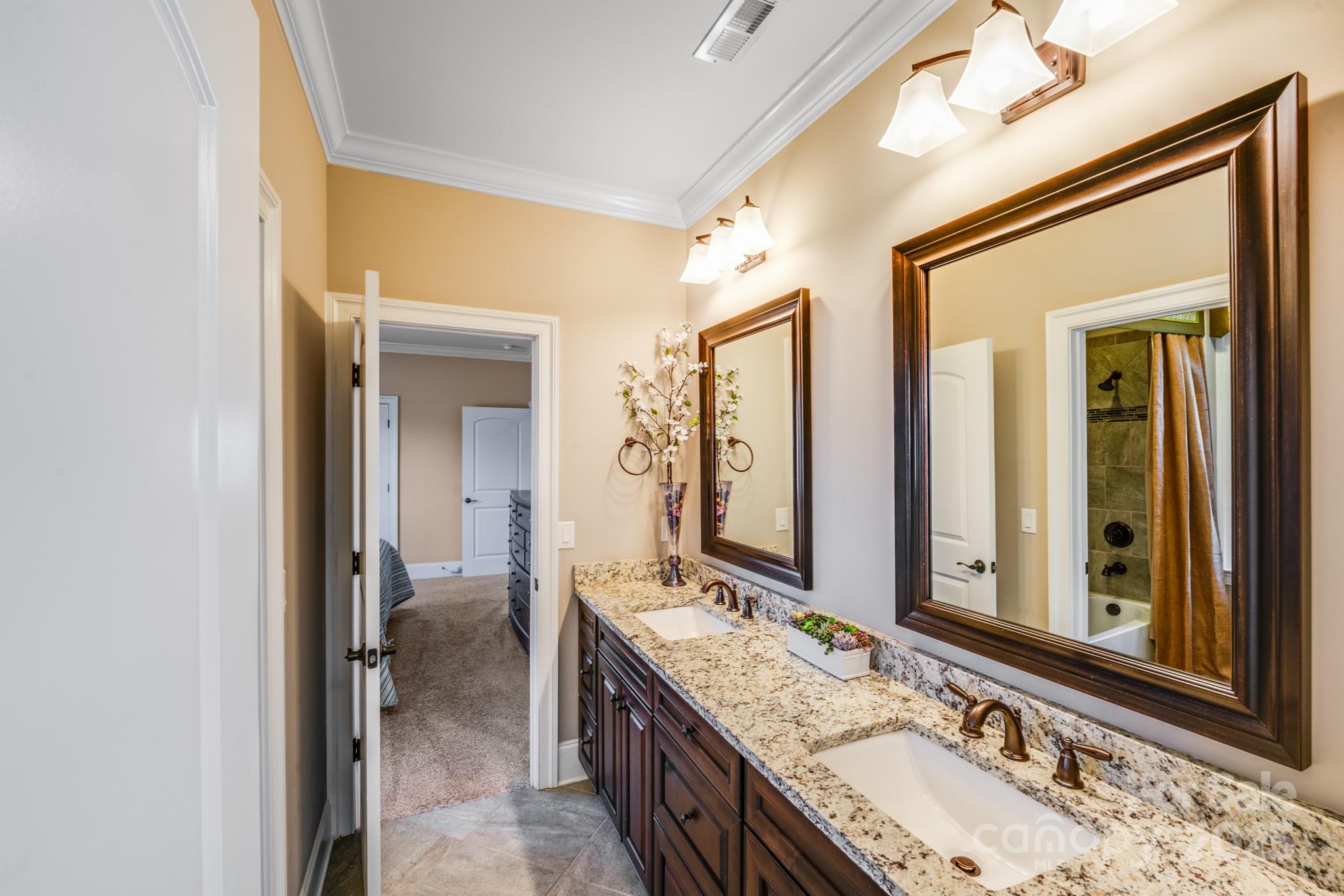 126 Forsythia Lane Tega Cay, SC 29708 - Photo 24 of 32 a en suite bathroom with a granite countertop double vanity sink a mirror and a shower