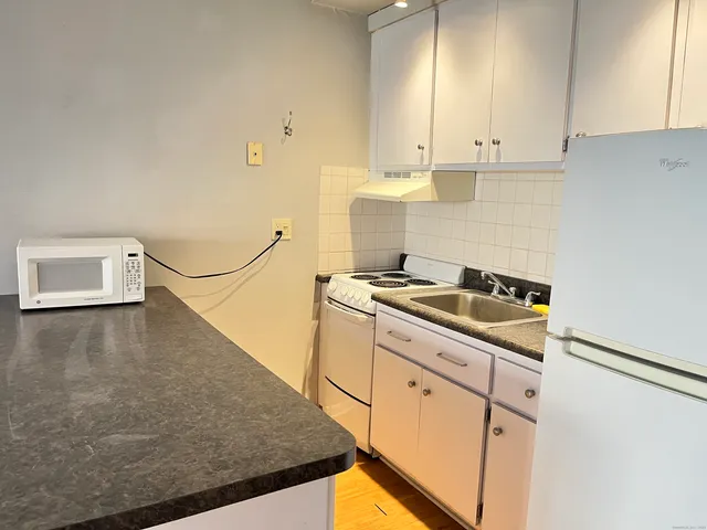 a kitchen with granite countertop a sink a stove and cabinets