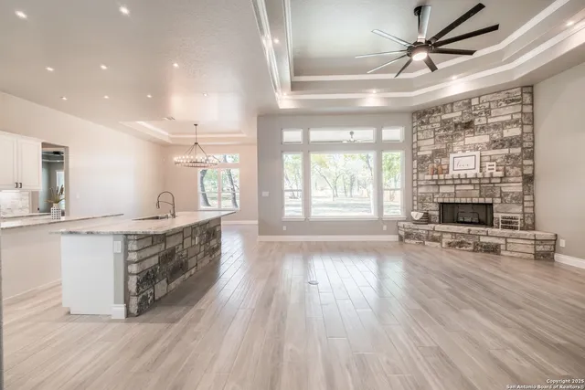 a view of an empty room with a fireplace and a ceiling fan
