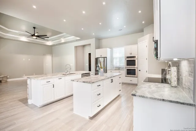 a large white kitchen with a stove a sink dishwasher and a fireplace with wooden floor