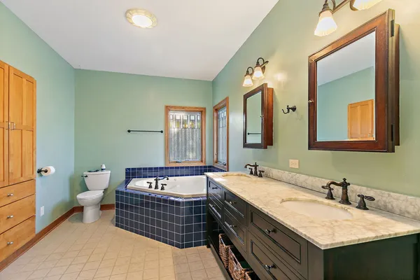 a bathroom with a tub double vanity sink and a mirror