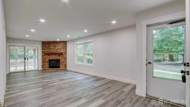 a view of an empty room with wooden floor and a fireplace