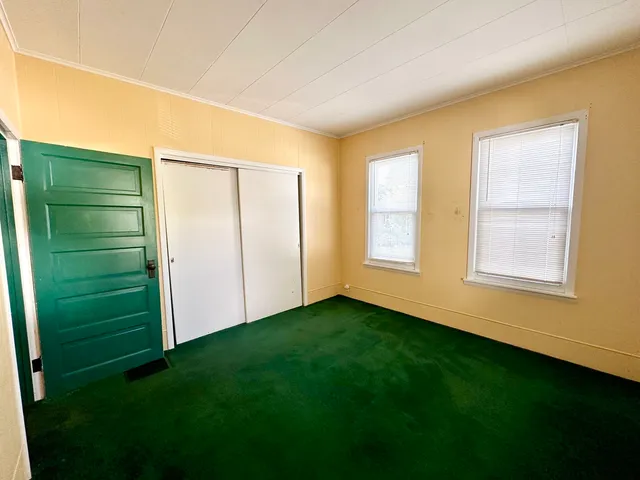 a view of an empty room with closet and a window