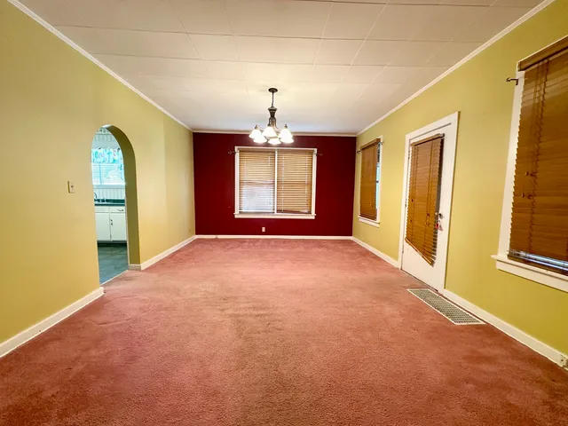 an empty room with windows and chandelier