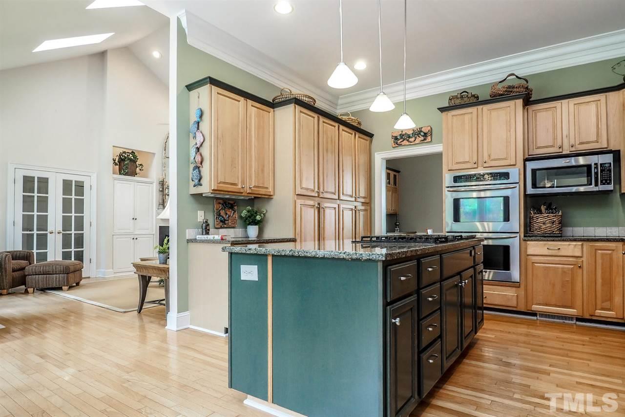 299 Howard Tant Road Zebulon, NC 27597 - Photo 7 of 25 The spacious eat-in Kitchen features lots of 42” maple cabs, granite ctrs, stone tile bksplsh above dbl sinks, SS appls (dbl wall ovens, MW, DW), big island w/4-burner gas cooktop, wall of tall pantry cabinets plus 2 pantry closets, & sunny Bfast area.