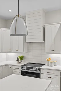 a kitchen with stainless steel appliances a stove a white cabinets and a window