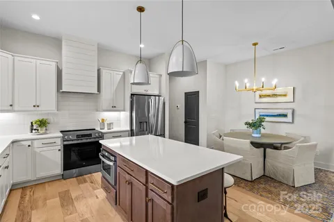 a kitchen with stainless steel appliances kitchen island a table chairs in it and a window