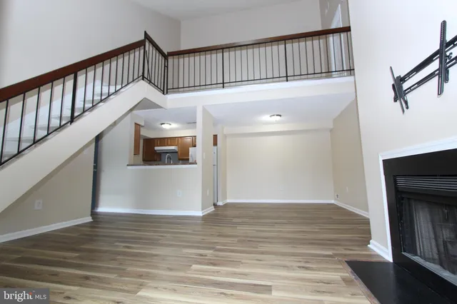 a view of an empty room with wooden floor and a fireplace