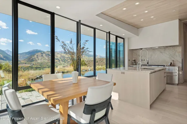 a view of an outdoor dining room with a table and floor to ceiling windows