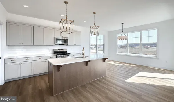 a kitchen with stainless steel appliances granite countertop a stove a sink dishwasher and a refrigerator with wooden floor