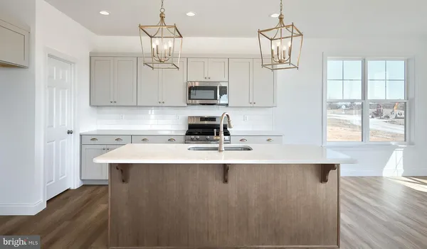 a kitchen with kitchen island granite countertop a sink a counter space appliances and cabinets