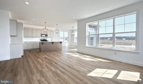 a large kitchen with stainless steel appliances wooden floor and a large window