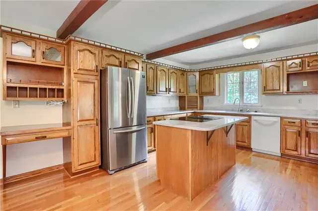 a kitchen with stainless steel appliances granite countertop a refrigerator a sink dishwasher a stove and a dining table with wooden floor