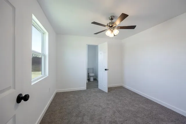 an empty room with a window and a fan