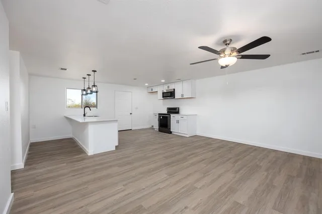 a view of a kitchen with a sink a ceiling fan and wooden floor