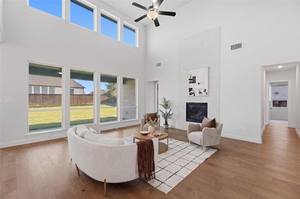 1316 Limestone Ridge Road Mansfield, TX 76063 - Photo 8 of 40 Vaulted ceiling living area featuring wood-finish flooring, a contemporary fireplace with a tall tiled surround, and multiple large windows