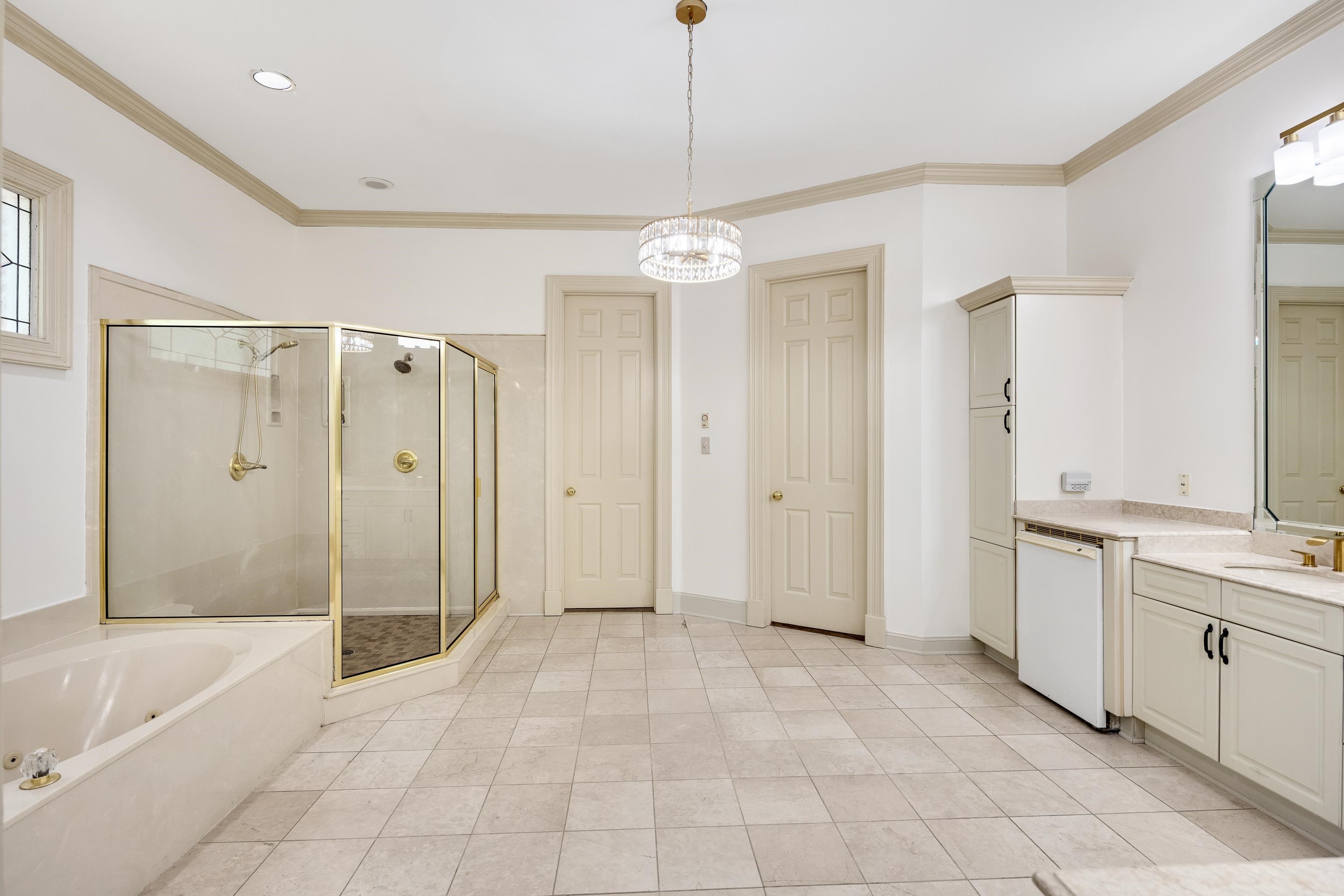350 Bluff Ridge Cove Memphis, TN 38018 - Photo 26 of 37 Spacious bathroom featuring a built-in tub, separate glass-enclosed shower with gold-tone fixtures, and dual vanities with integrated sinks